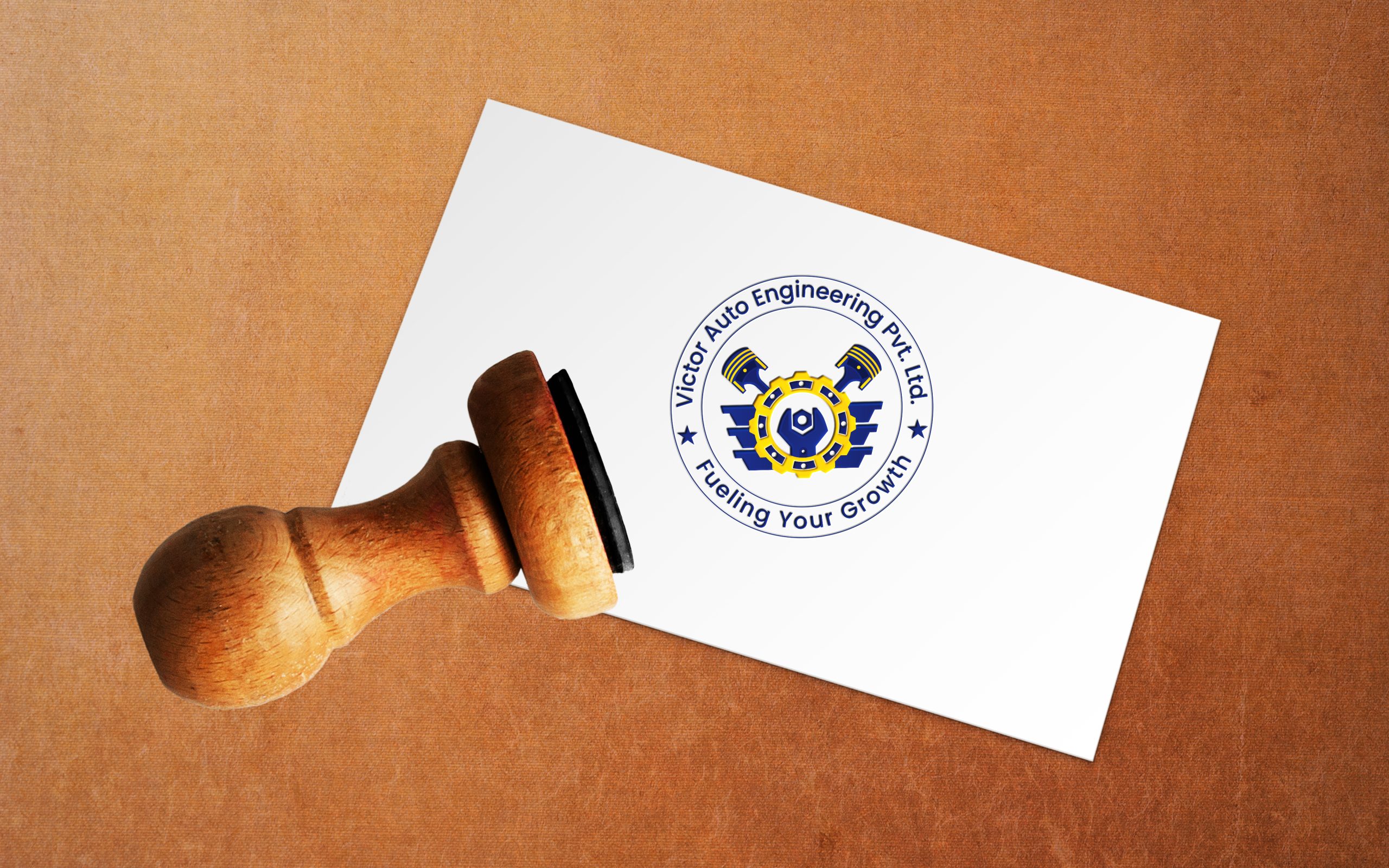 Wooden stamp pressing the "Victor Auto Engineering Pvt. Ltd." logo onto a white surface, with the tagline "Fueling Your Growth."