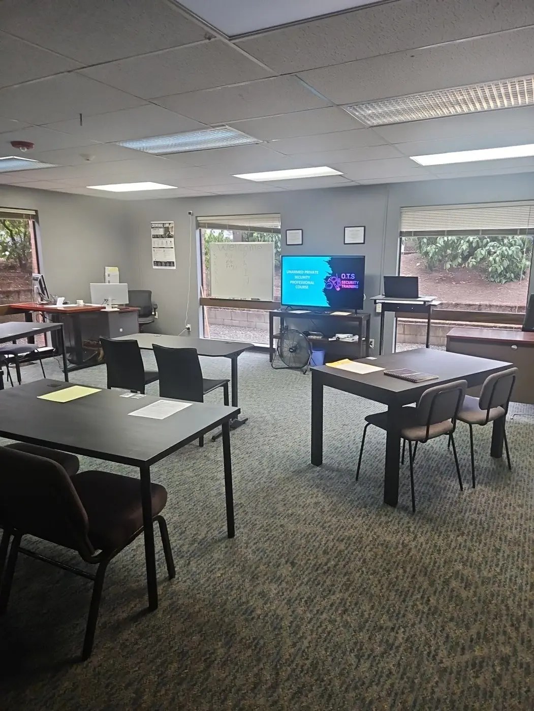 OTS Security Training classroom in Portland with tables, chairs, and an unarmed private security course displayed on the presentation screen