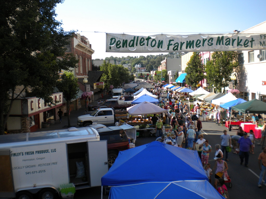Colorful produce stalls at the Pendleton Farmers Market on a summer morning