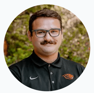 Professional headshot of man wearing glasses and a black polo shirt