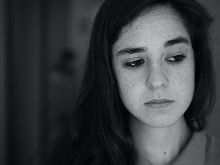 Black and white photo of a person looking downcast.