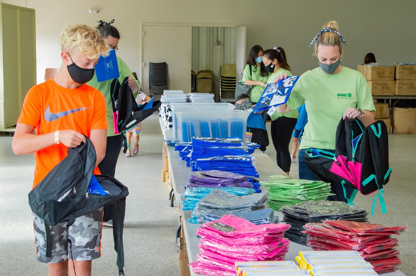 OUC employees and family members stuff backpacks that will be delivered to students in need.