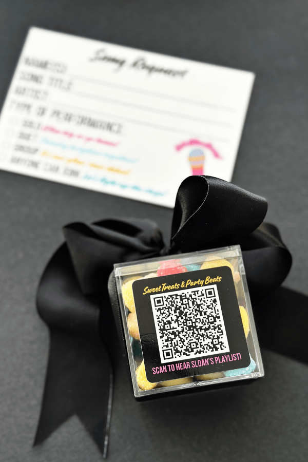 Party favor box with QR code playlist sticker and gummy candy inside for karaoke party, with song request card behind.