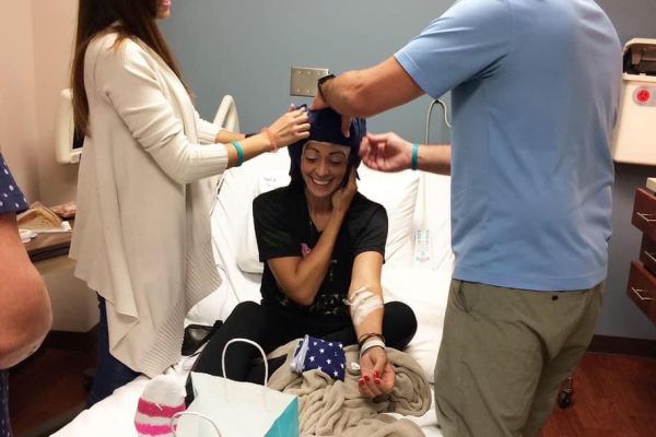A female ovarian cancer patient in the hospital with two visitors helping her with a cool cap