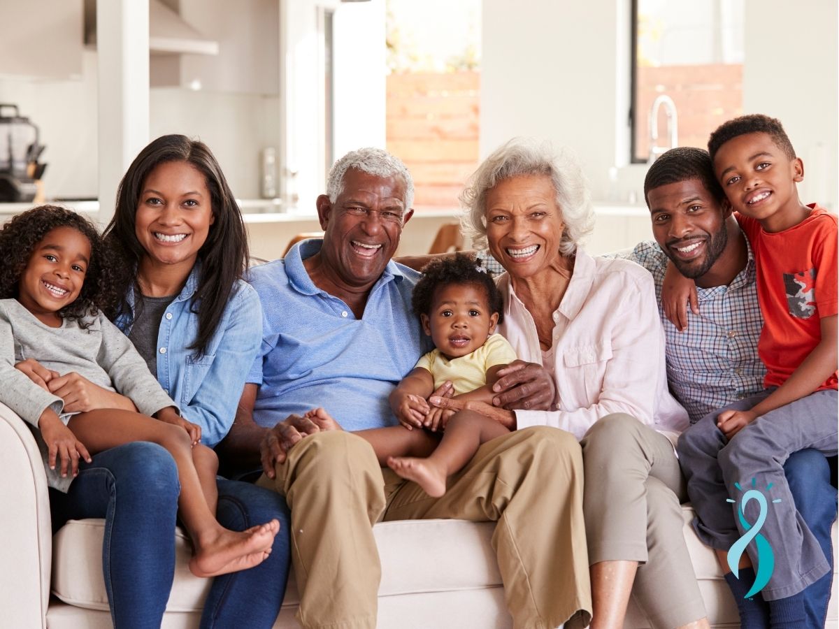 A multi-generational family sitting together on a couch, smiling and engaging warmly, representing the importance of knowing your family health history in understanding and addressing ovarian cancer treatment options.