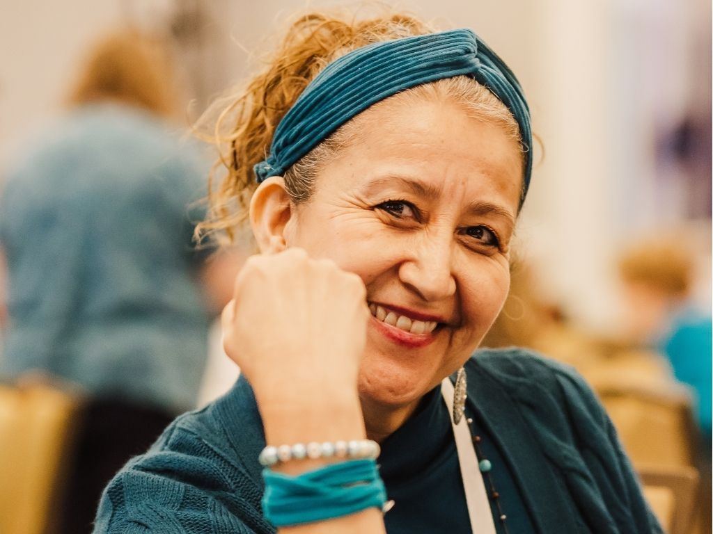 Ovarian cancer survivor wearing a teal headband smiles while attending an ovarian cancer conference.