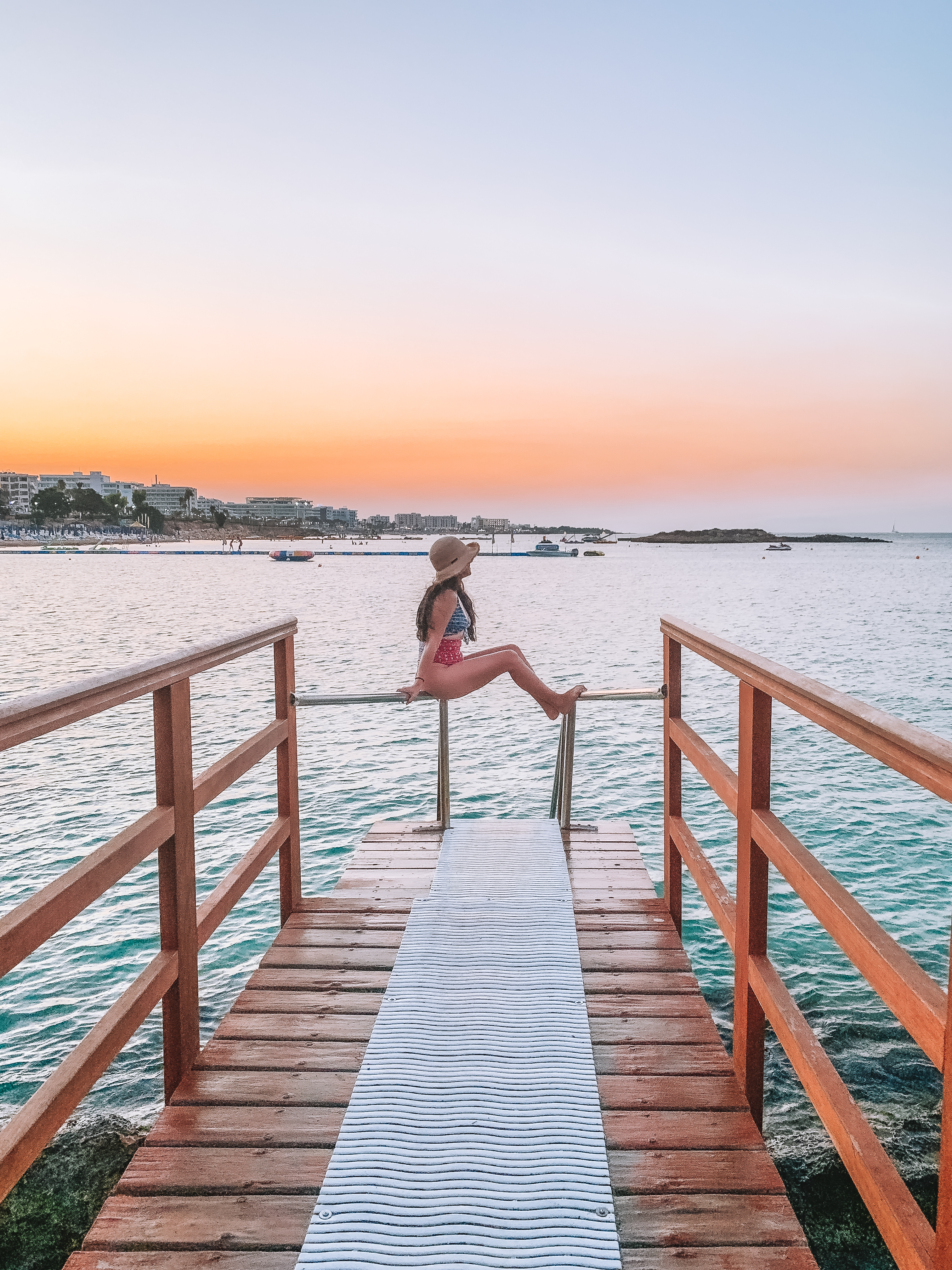 Girl sitting at the end of a walkway near the water