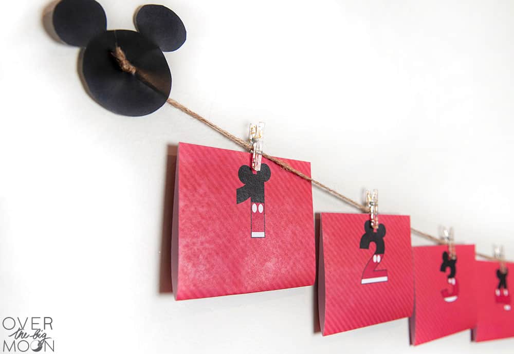 A disney countdown created using printables, twine and clips hanging on the wall.