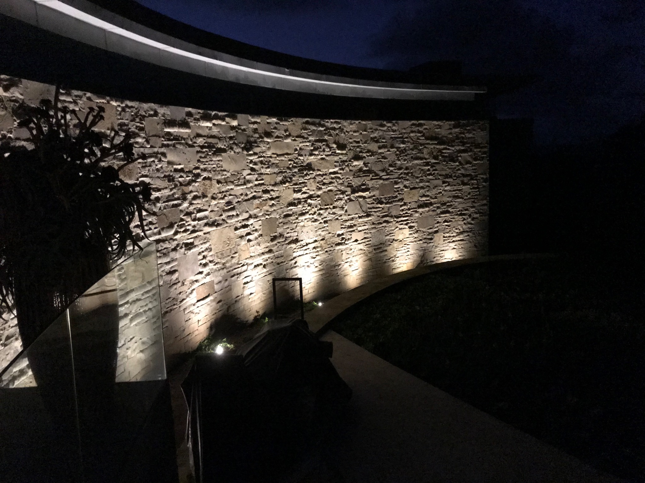 Architectural lighting highlighting a curved stone wall at night