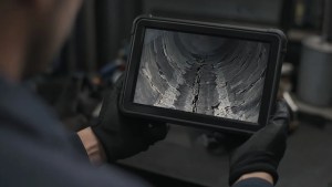 Tablet showing cracked soot-lined flue during Level 2 chimney inspection
