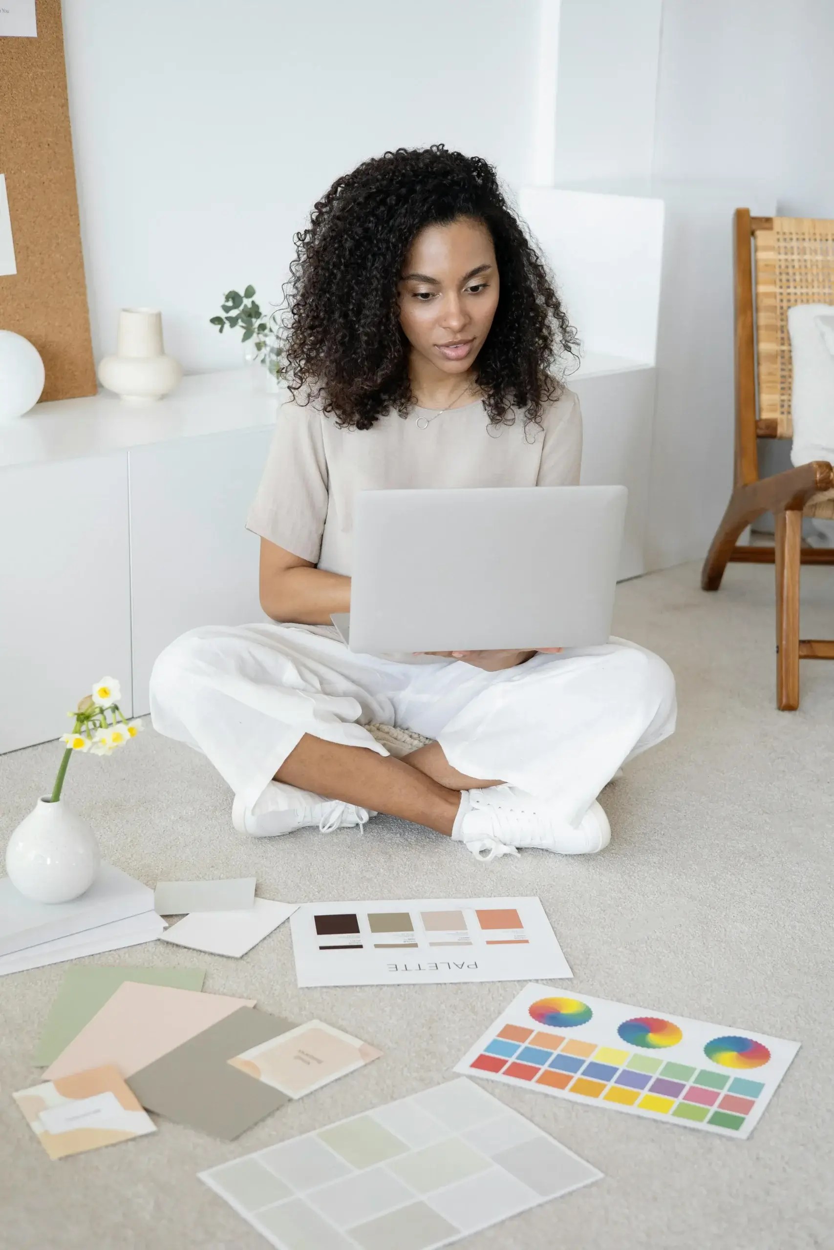 Woman sitting on the floor using a laptop with color palettes, representing ADHD hyperfocus and creativity