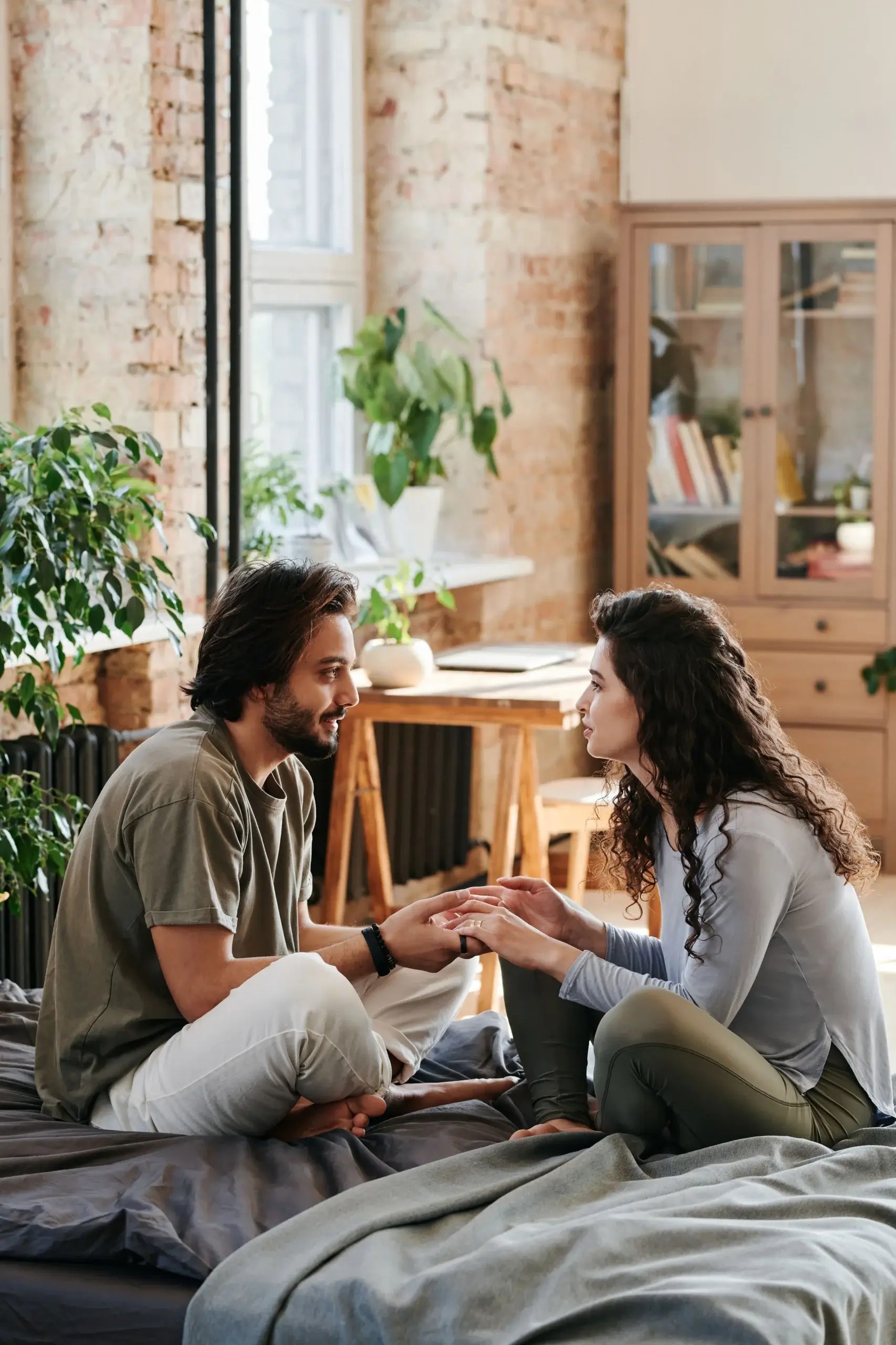 Couple sitting face-to-face and holding hands during an emotional conversation.