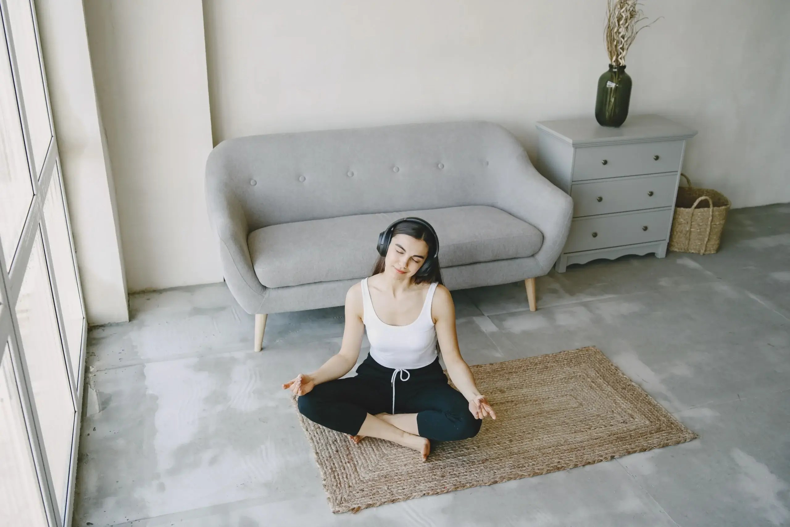 Person sitting cross-legged on a rug practicing mindful breathing at home, illustrating nervous system regulation during a calm moment.