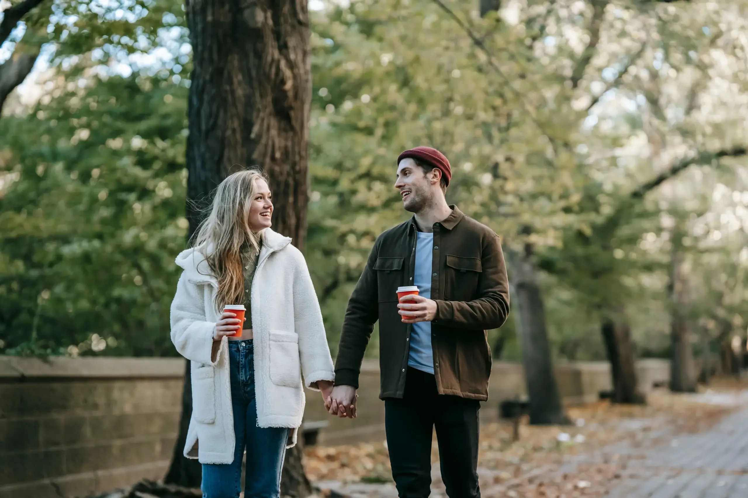 Couple walking hand in hand through a park, illustrating how curiosity and emotional openness strengthen connection in relationships.