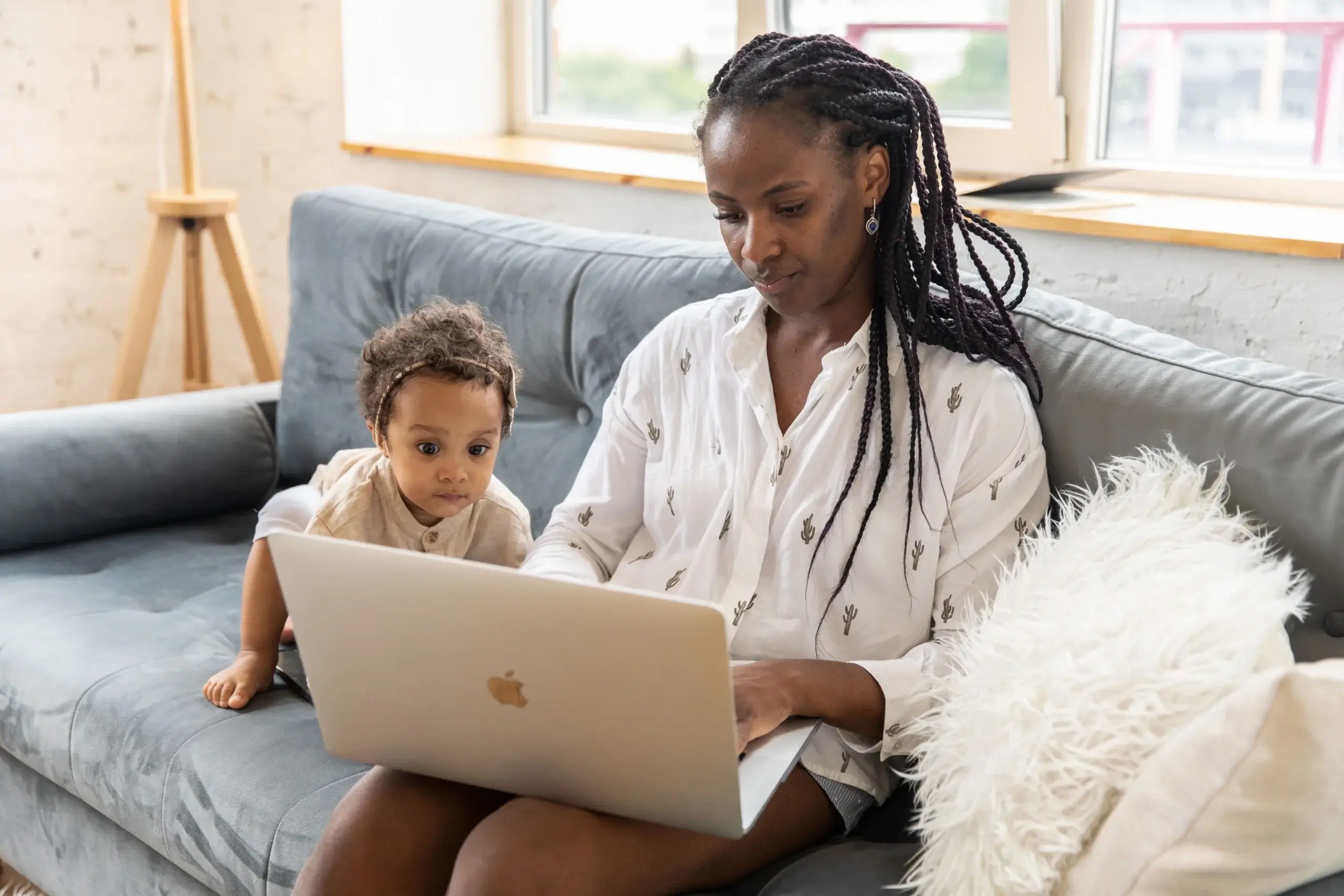 Woman working on a laptop while caring for a young child, illustrating how increasing life demands can overwhelm coping strategies for women with ADHD.