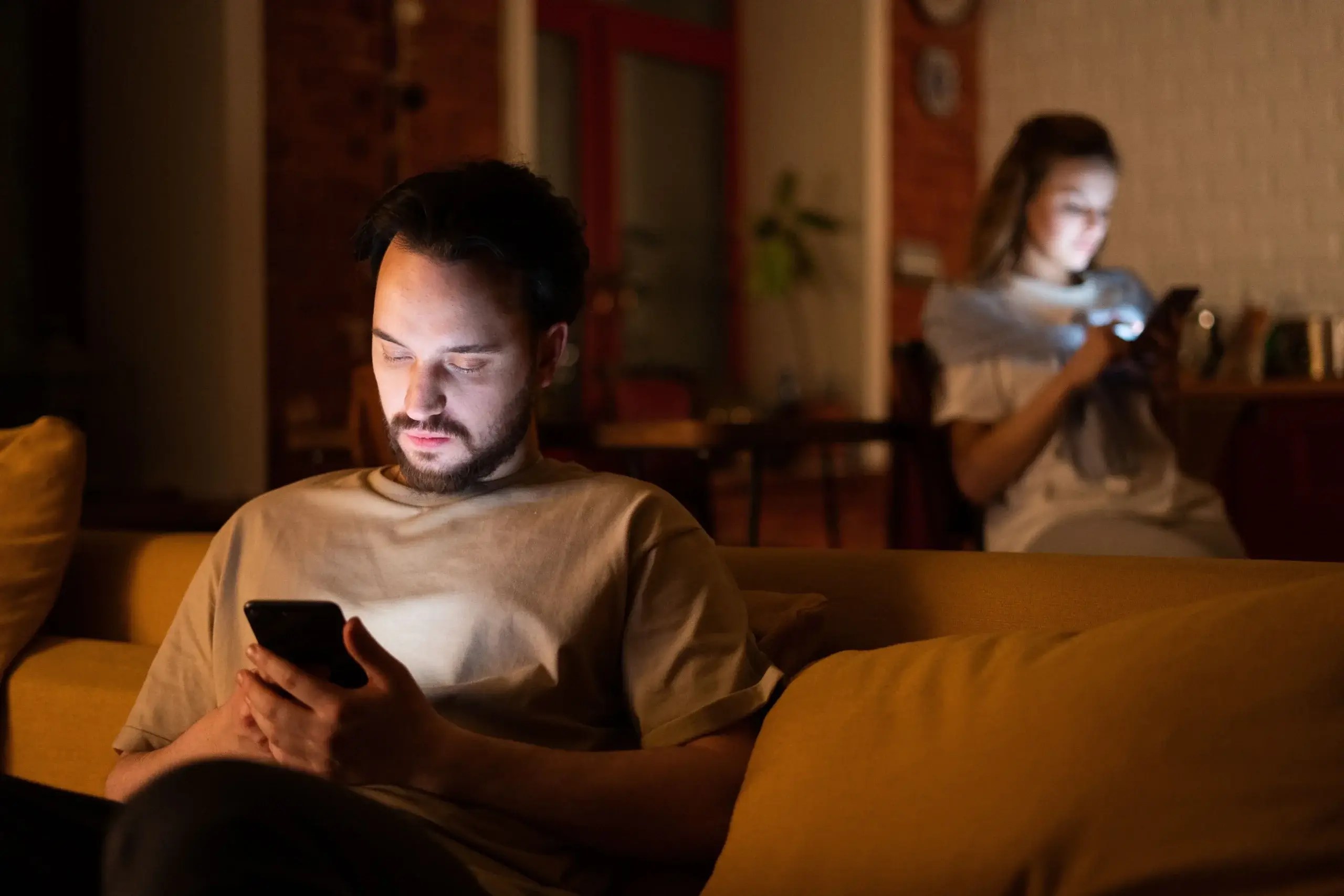 Couple sitting apart and looking at their phones during a moment of emotional distance