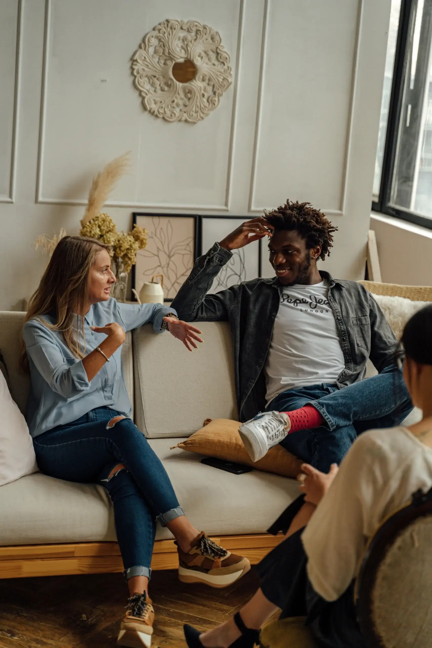 Three adults having a thoughtful conversation about relationships in a warm, comfortable setting
