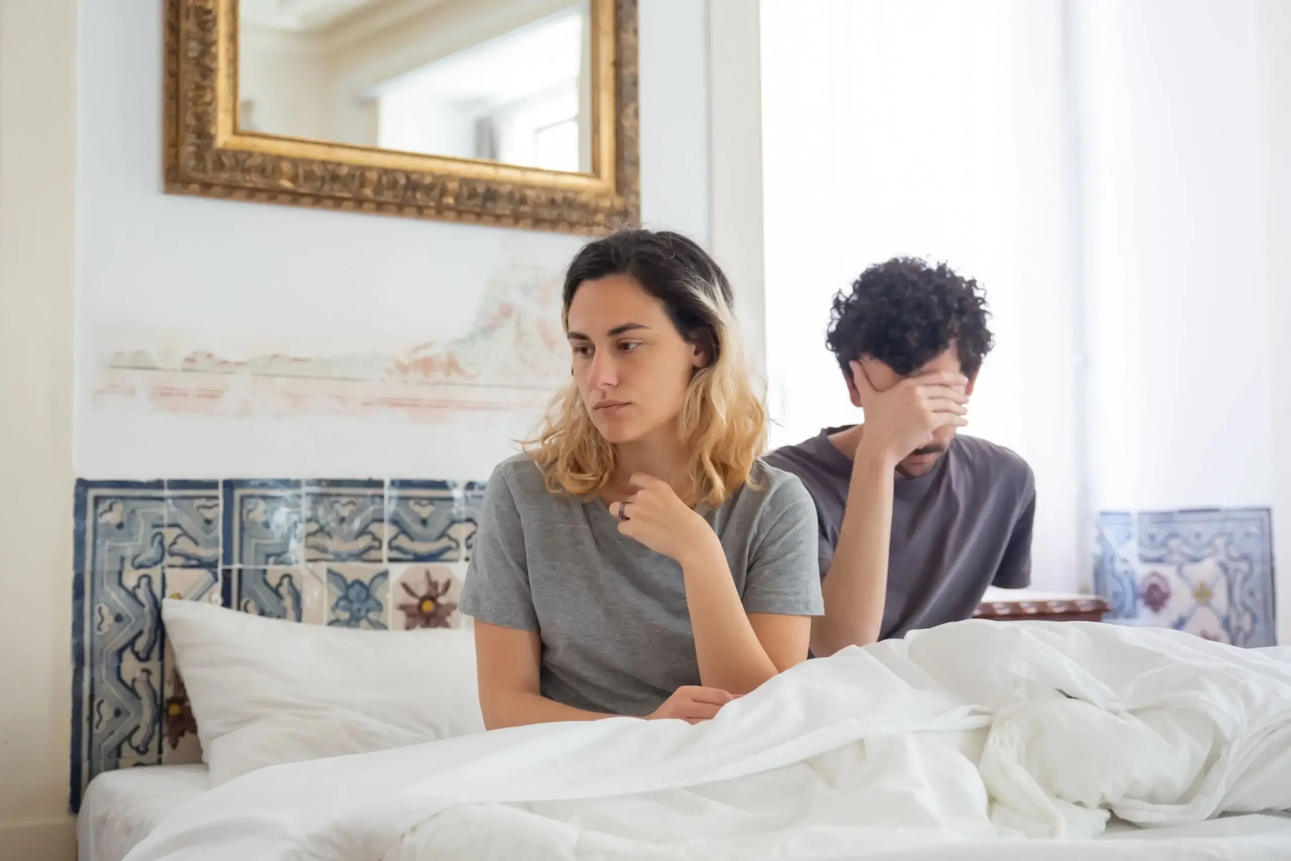 Couple sitting on bed experiencing emotional distance and low sexual desire