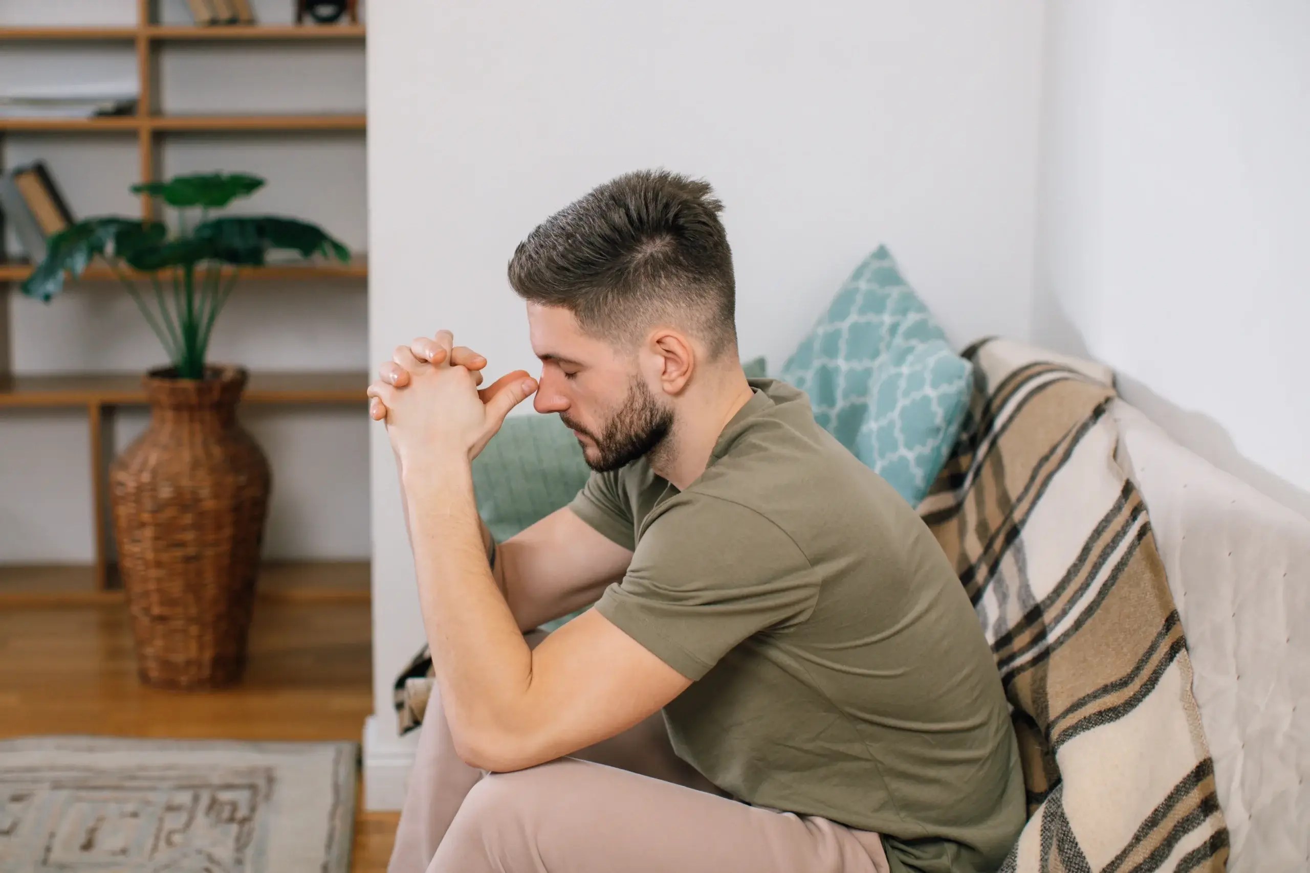 Man sitting on a couch experiencing emotional distress and overwhelm
