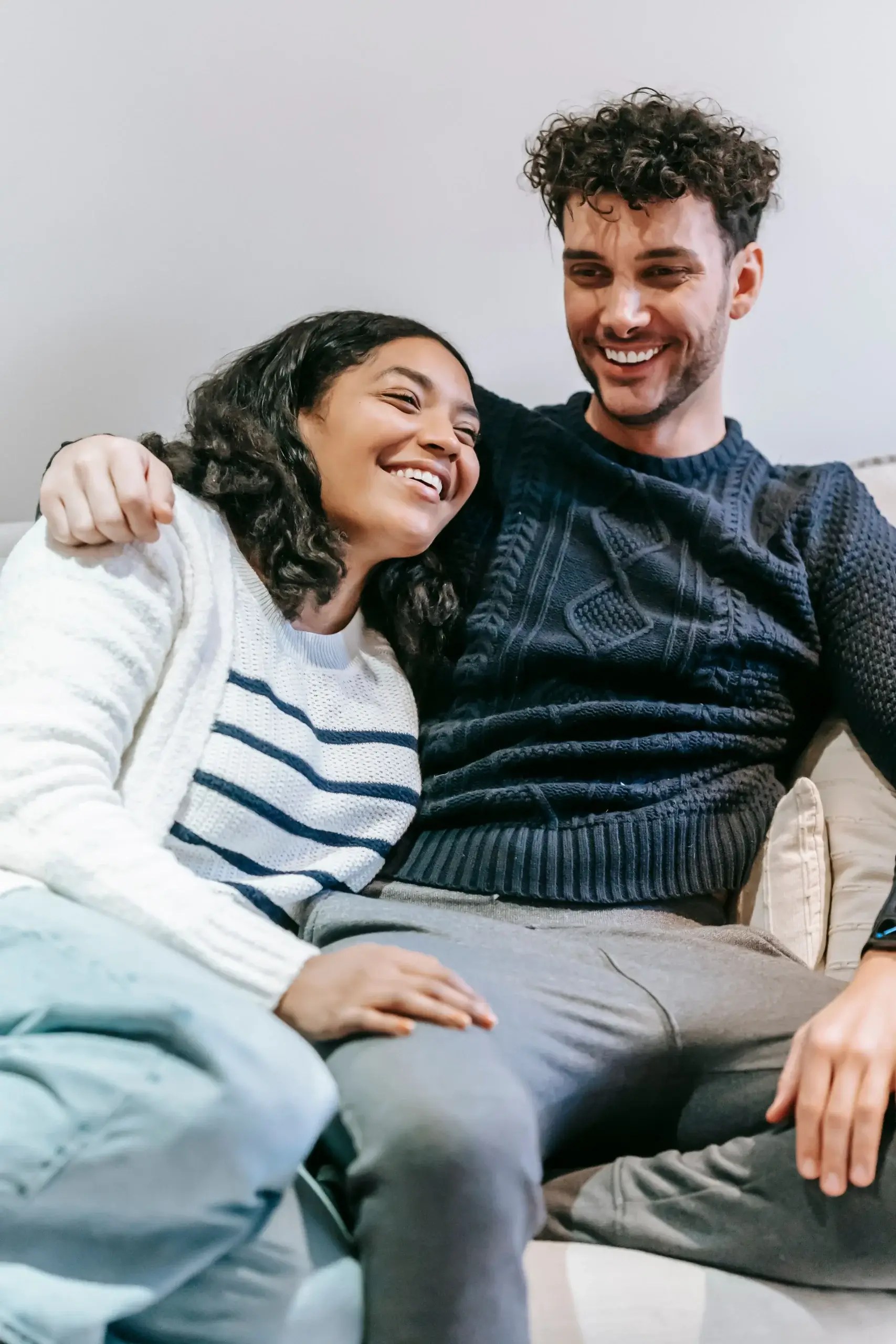 Couple sitting closely together and smiling, illustrating reconnection and emotional closeness after relationship conflict.