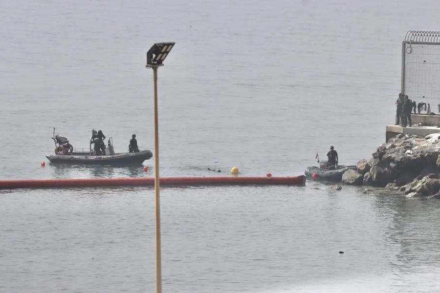 Colocación de una boya flotante para marcar el límite entre la playa del Tarajal de Ceuta y Marruecos, tras la entrada masiva de personas en los últimos días. EFE/Reduan.