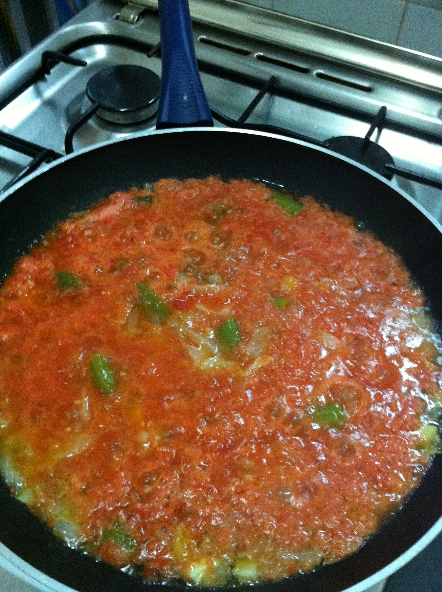 Sartén donde se está sofriendo tomate, cebolla y pimiento.
