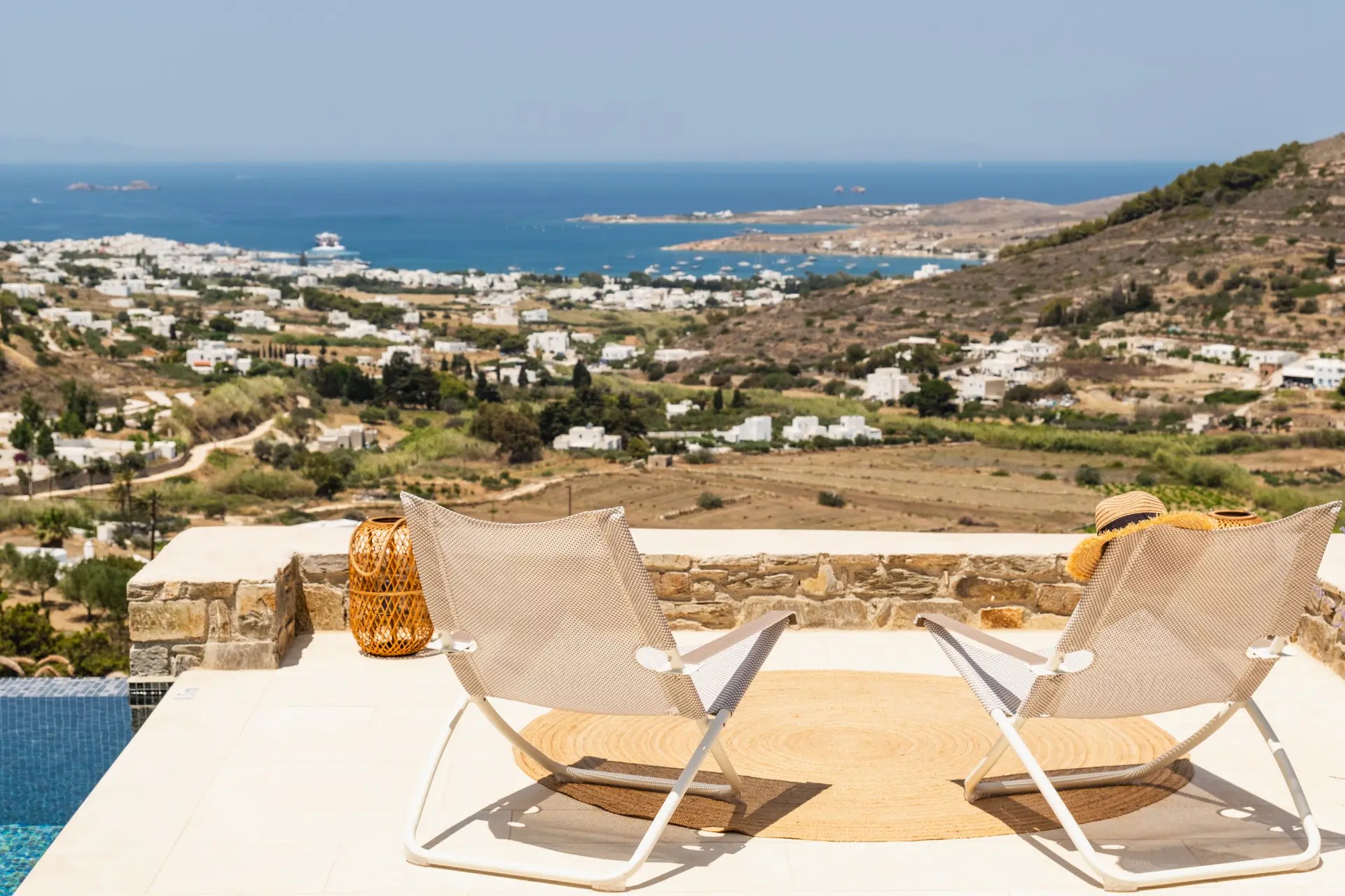 Terrace with loungers at a luxury Paros villa, offering panoramic views of the Aegean Sea and Paros countryside.