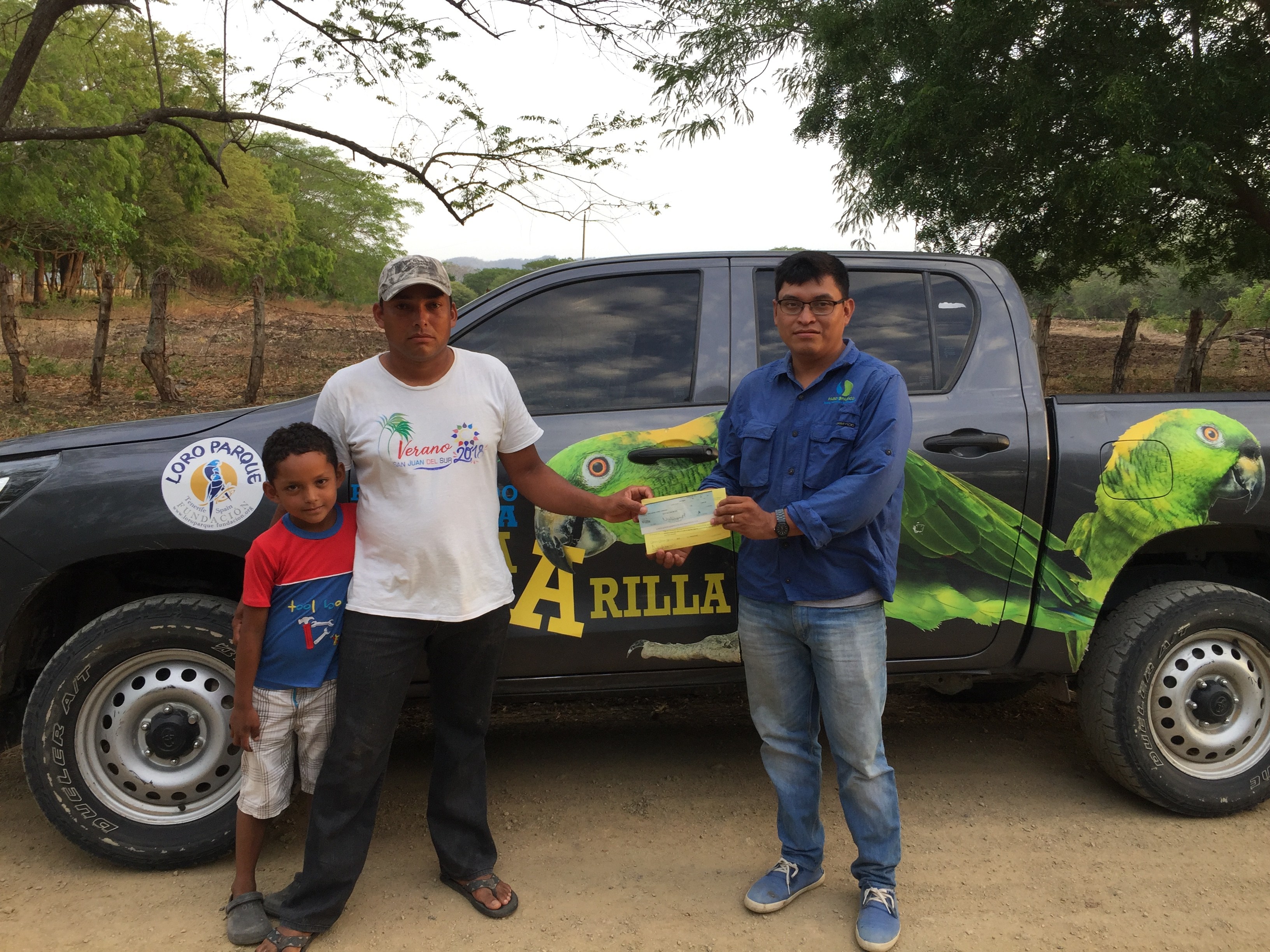 Marcos Calero delivers incentives to a family of parrot protectors in front of the parrot-adorned truck funded by Loro Parque Fundacion.