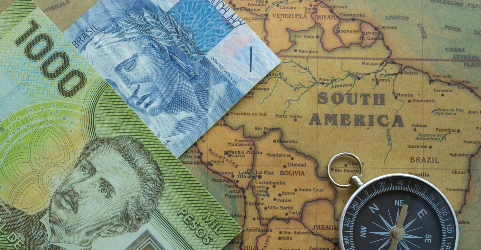 Mapa de quem preparo financeiro para estar viajando pela América do sul sobreposto com dinherio chileno, brasileiro e uma bússola.