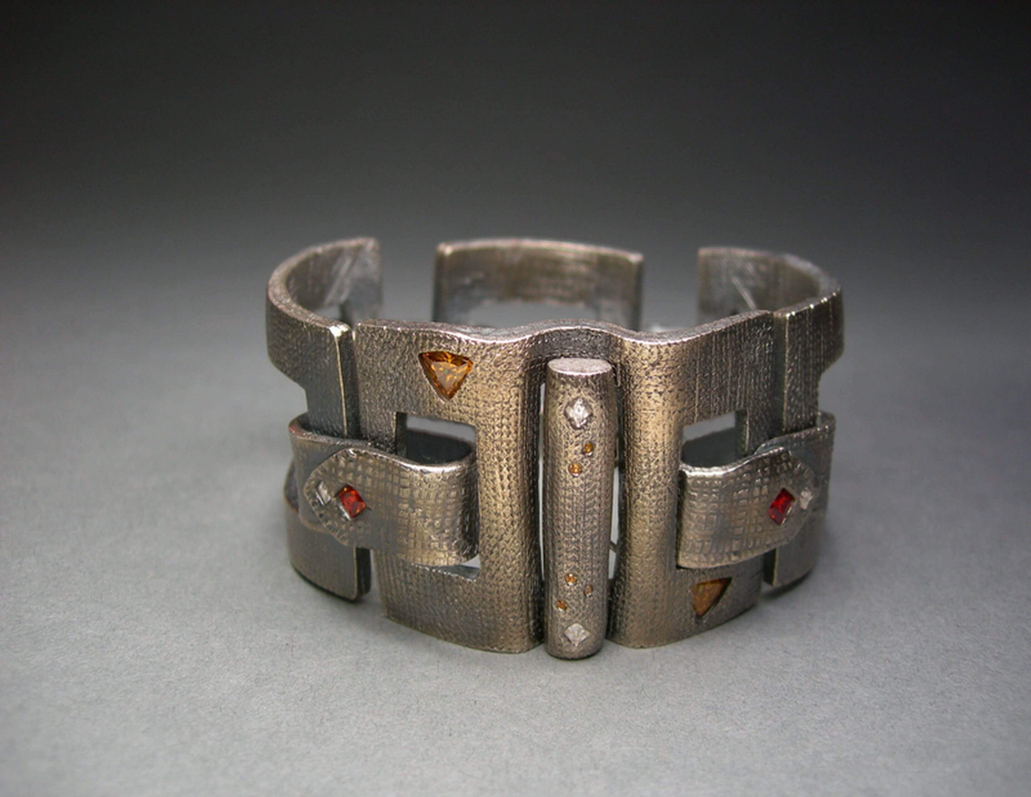 Metal bracelet with geometric design and stones.