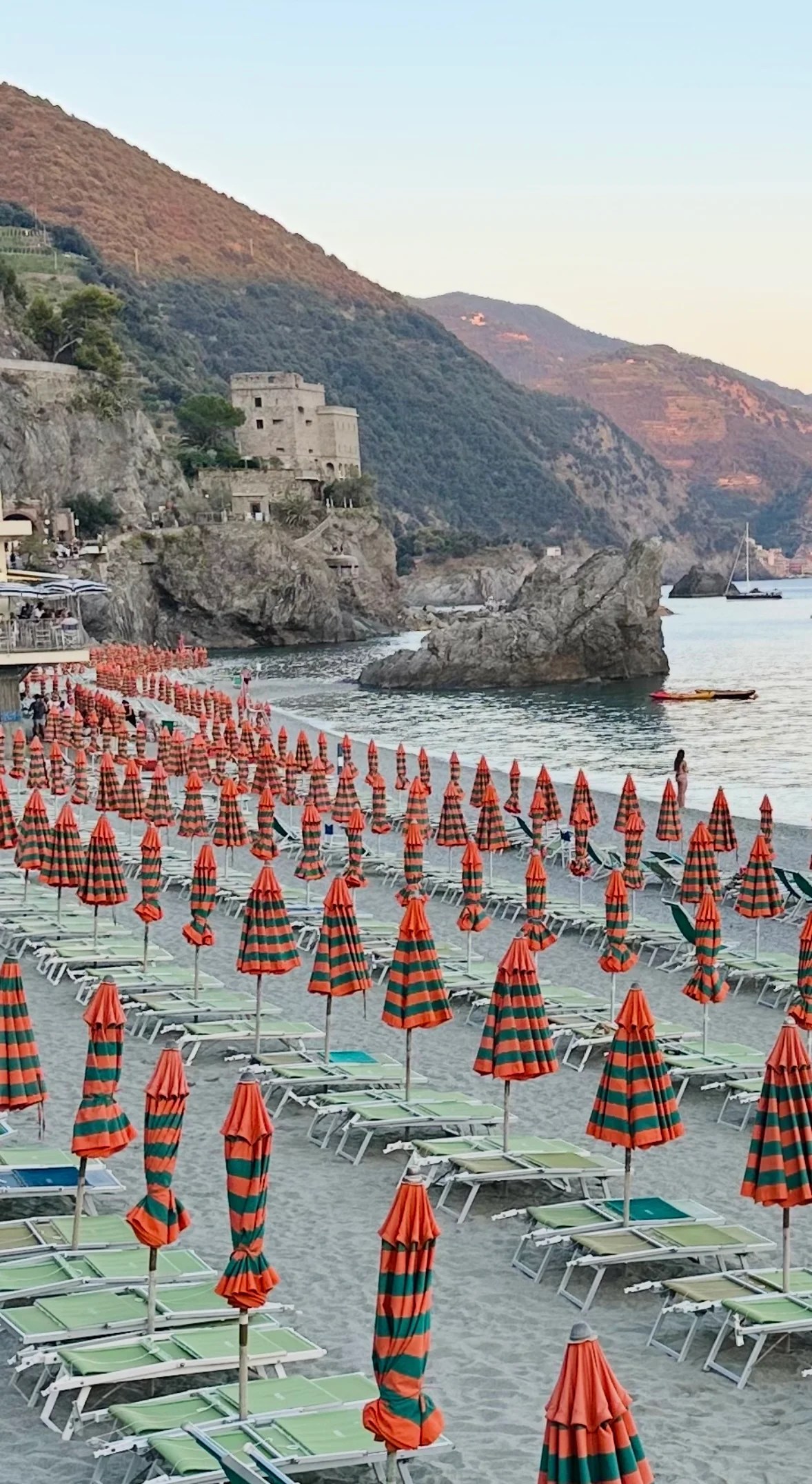 Monterosso beach in Cinque Terre, Italy with iconic orange and green umbrellas along the shore