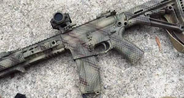 Rattle-can spray-painted AR-15 with matte camo scheme; field-expedient coating providing low-cost visual customization with minimal durability or chemical resistance.