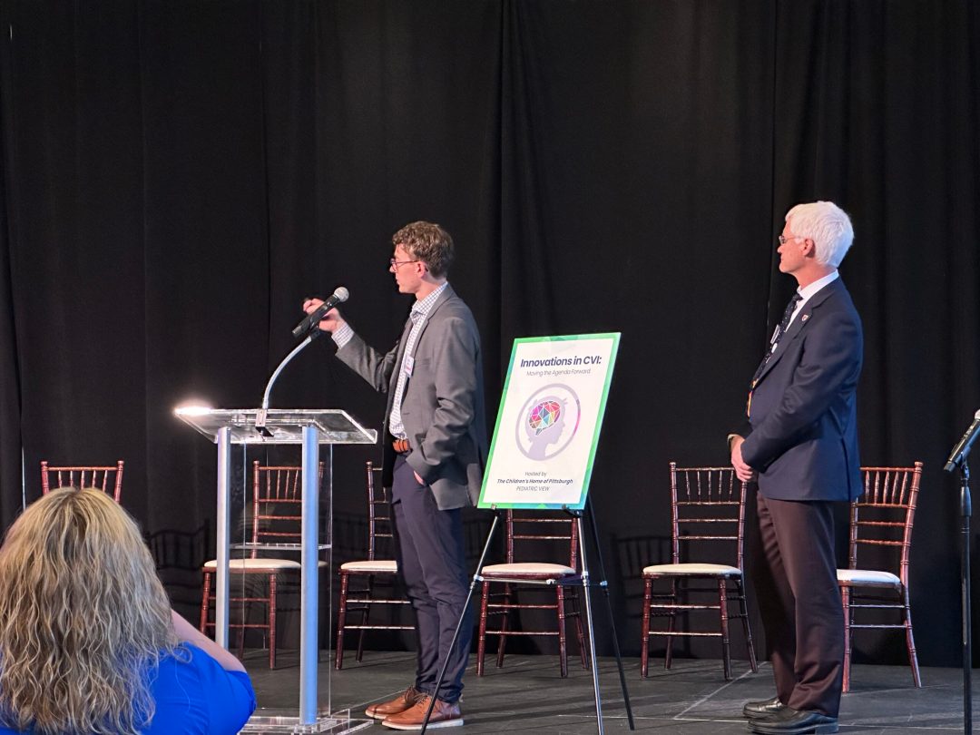 Paper authors John Rogers and Richard Legge present from stage.