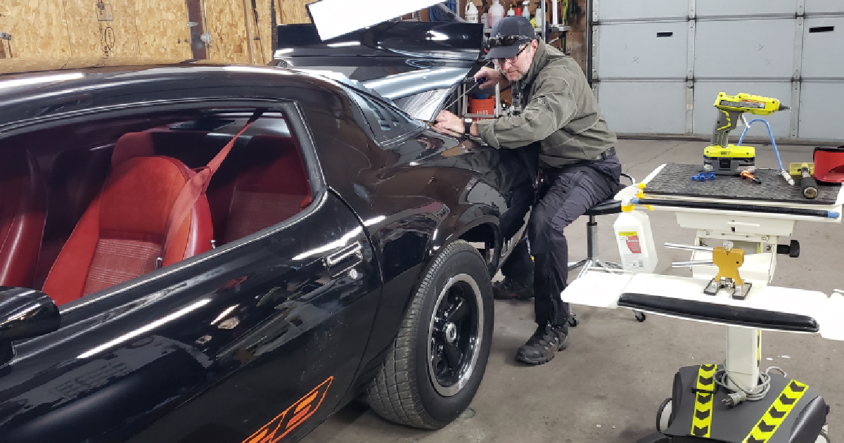CAR IN BODY SHOP BEING REPAIRED By paintless dent repair technology.