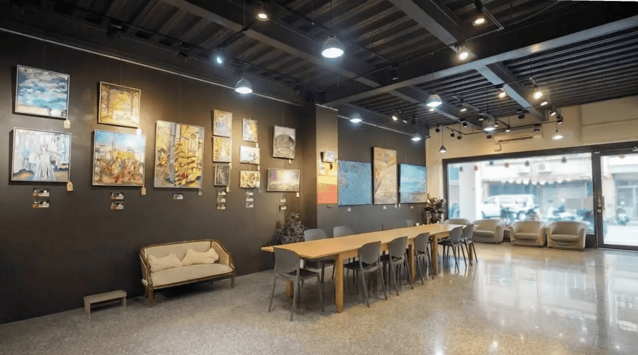 藝術教室大廳空間，牆面展示學生藝術作品，中央長桌與座椅提供上課與交流使用，整體明亮寬敞、具展覽氛圍。