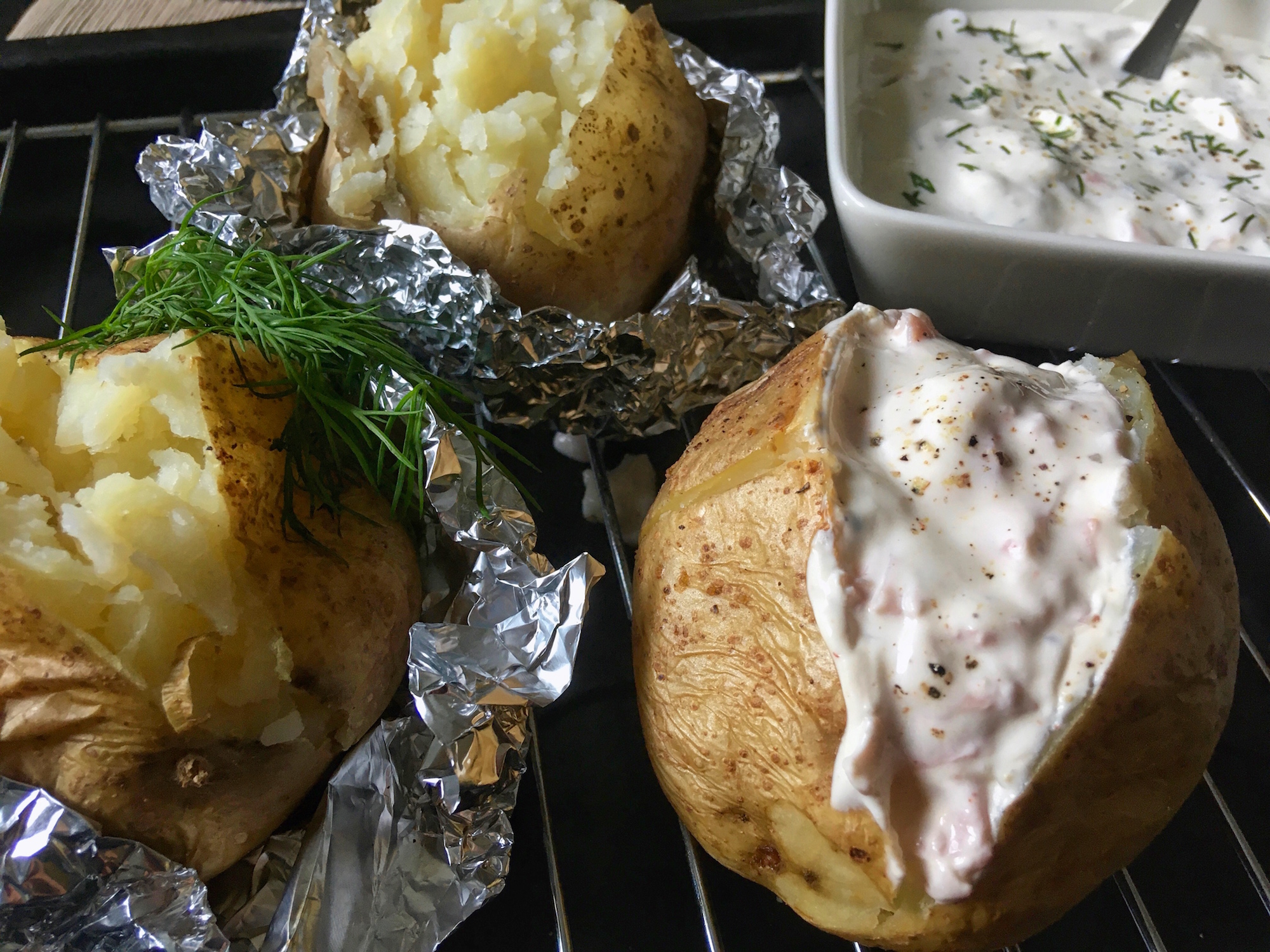 Close-up of cooked baked potatoes cut half open with a side of salmon filling