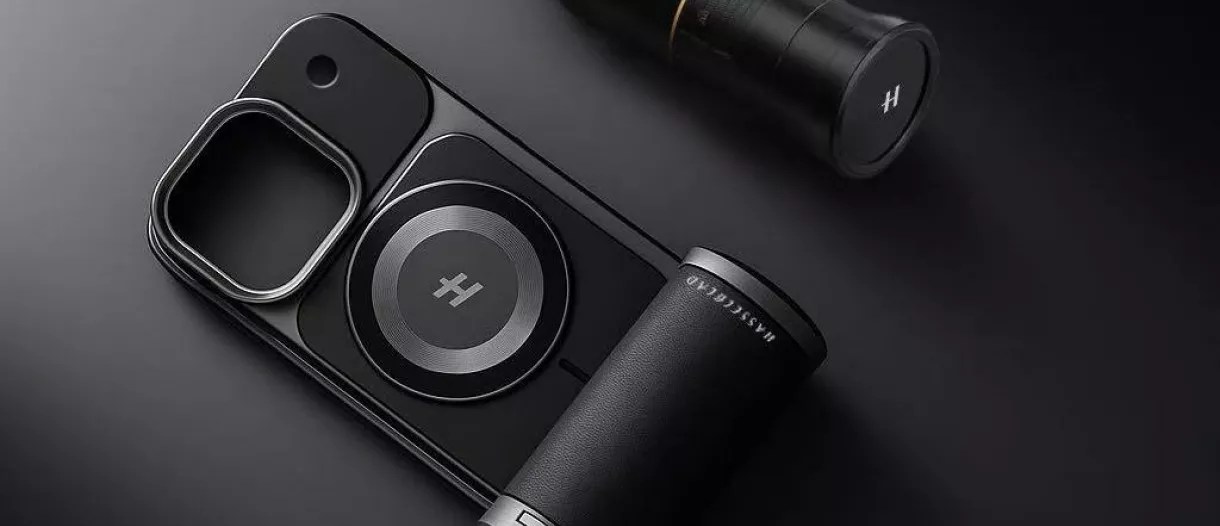 Aksesori kamera smartphone hitam dengan Teknologi Hasselblad dan cincin magnetik, diletakkan di samping lensa kamera eksternal, di latar belakang gelap.