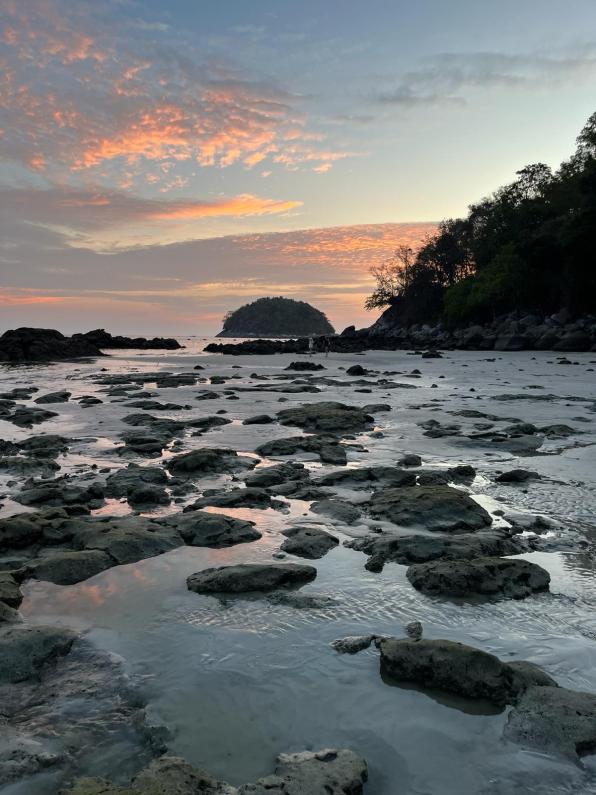 A sunset over a rocky beach on Phuket Thailand