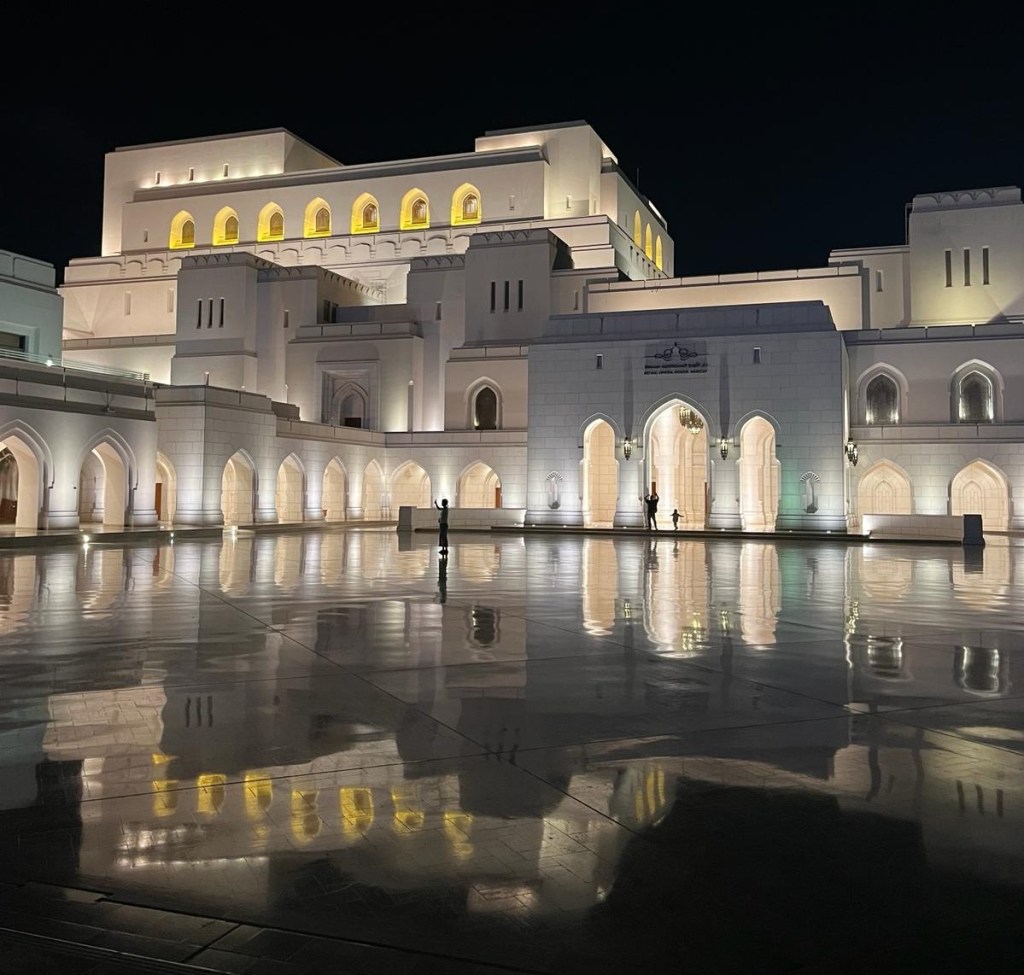 The Muscat Royal Opera House lit up at night.