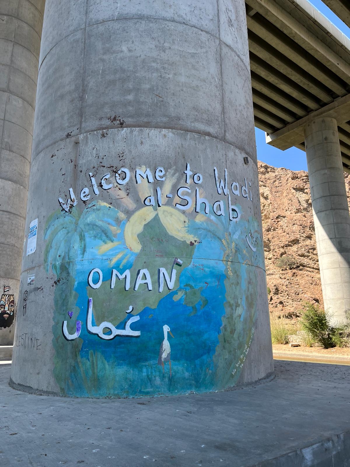 The Welcome to Wadi Shab graffiti on the highway bridge overpass.