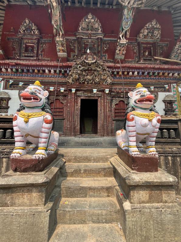 Two white dog statues guarding a wooden temple in Kathmandu Nepal