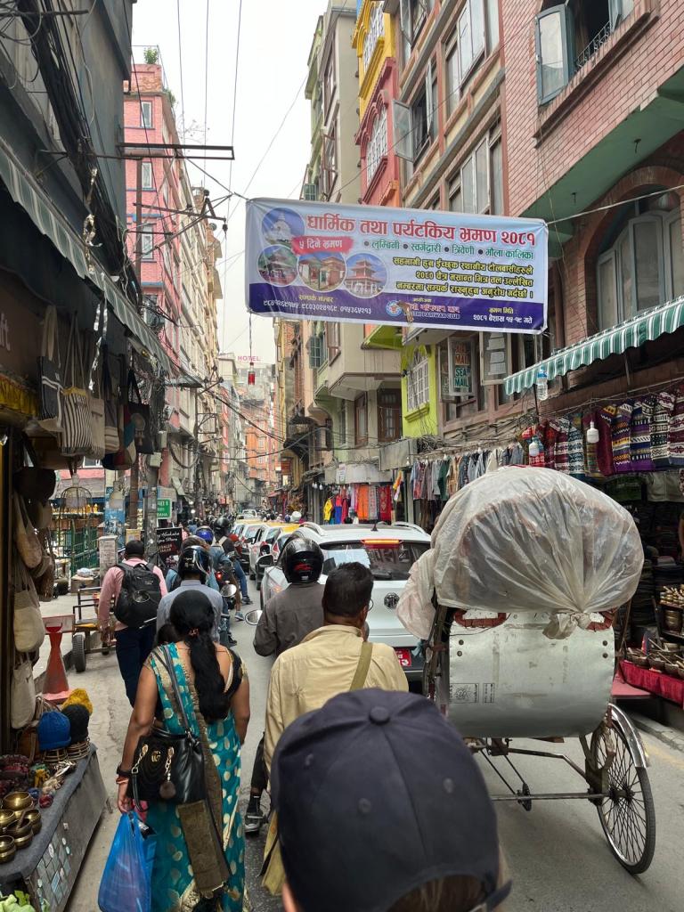 Thamel neighborhood busy street with walker, cars and carriages.