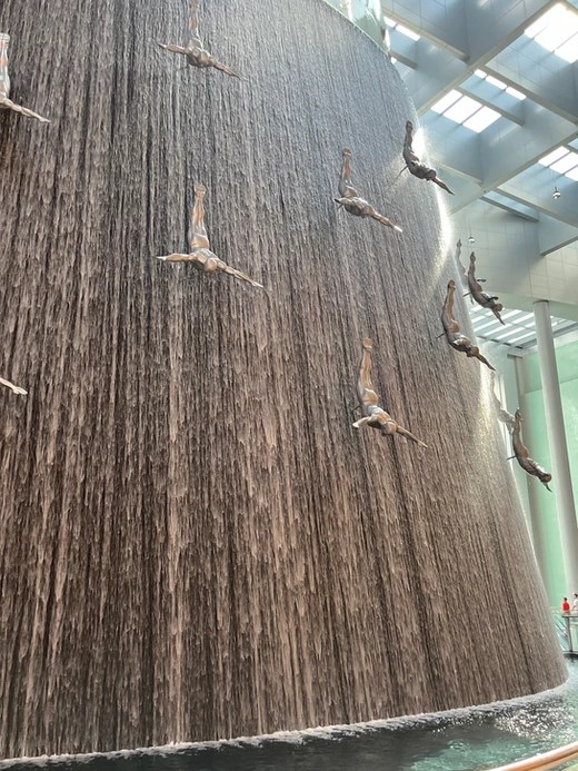 The waterfall with an art instillation of men diving at Dubai Mall
