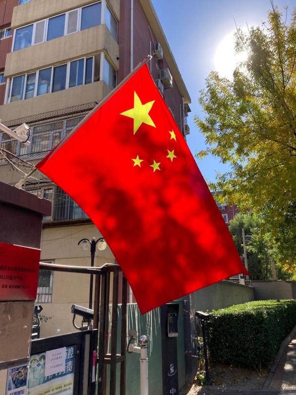 The flag of China prominently displayed with the sun shining behind it.