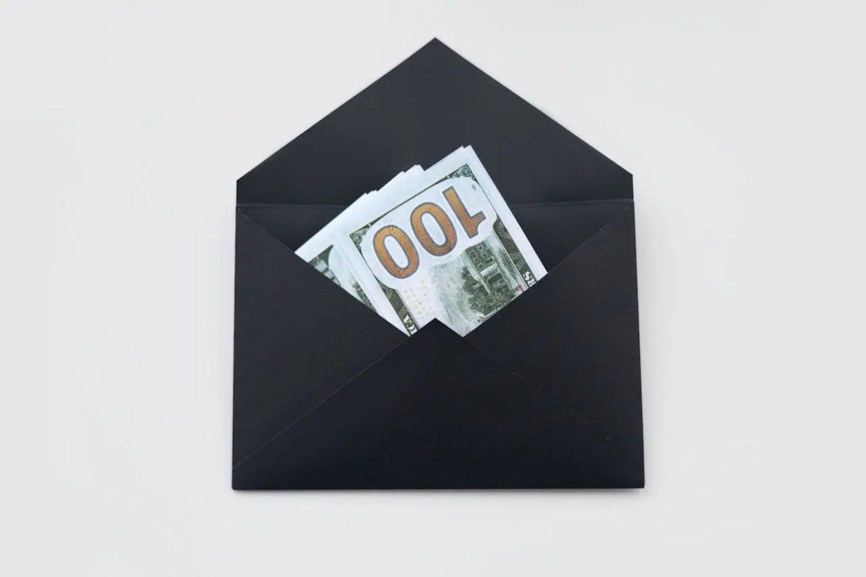 envelope-for-first-$100k A black envelope filled with money, representing savings and financial growth toward achieving the first $100K for FIRE.