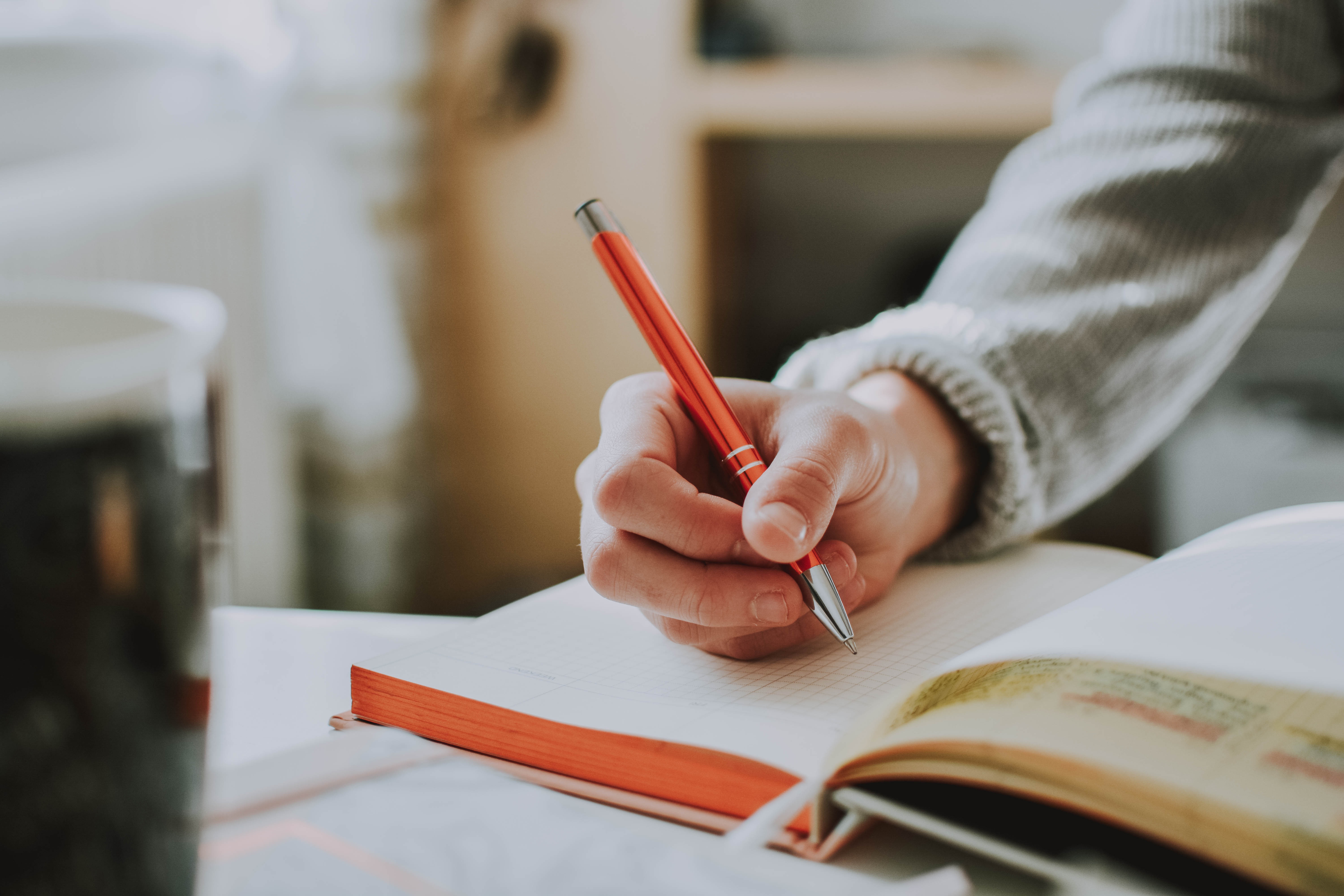 A hand holding an orange pen