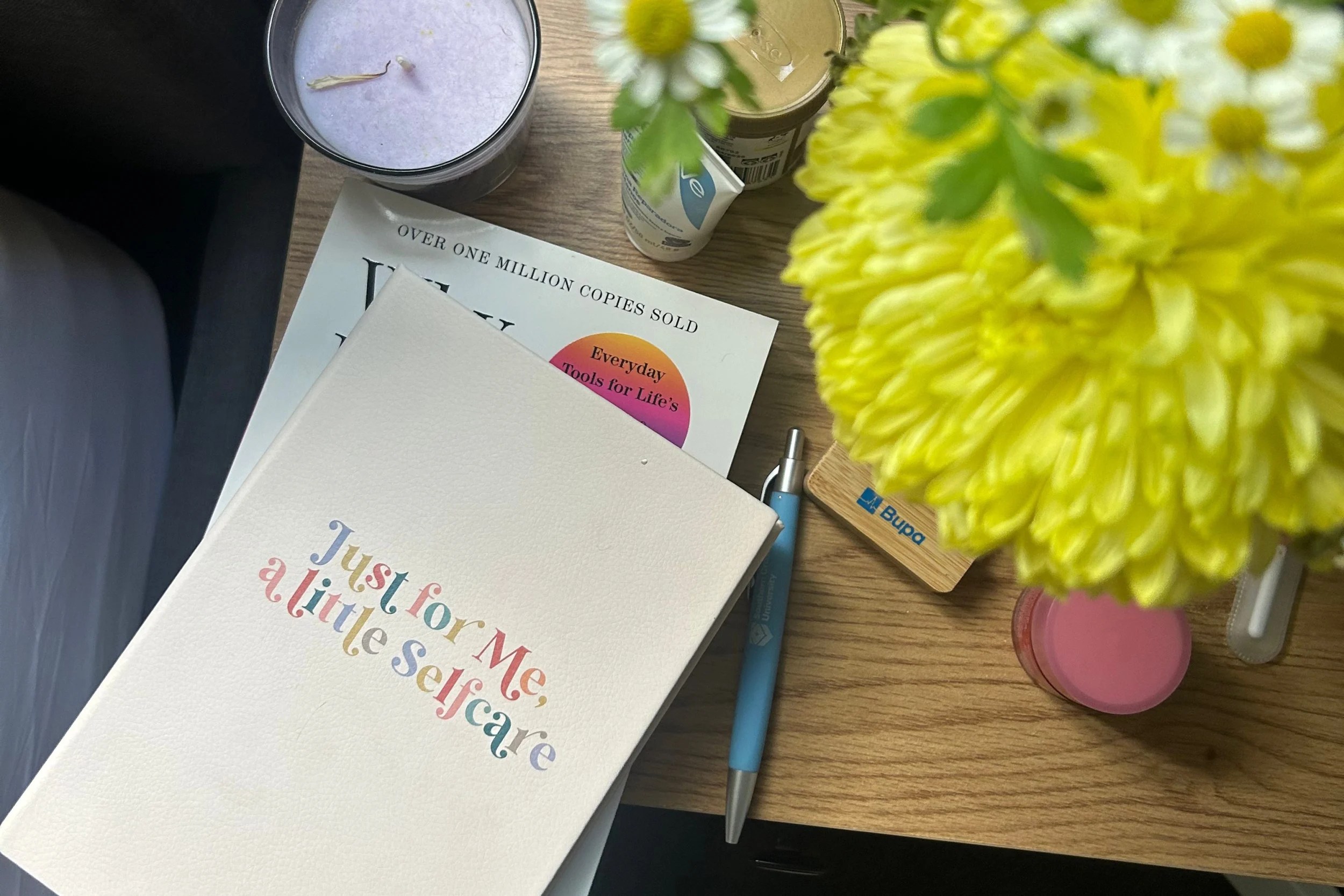 Self care journal, books and yellow flowers on a table