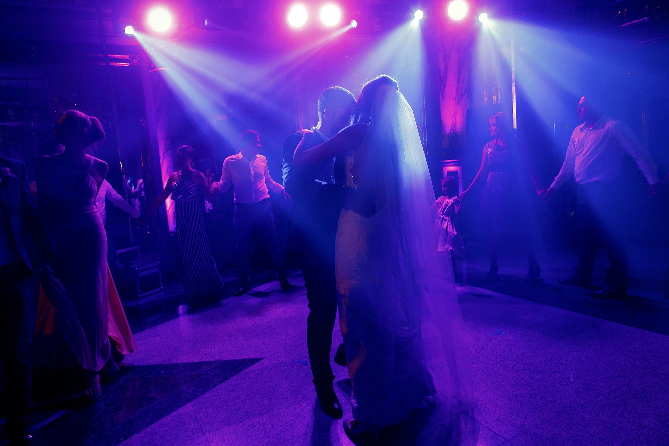 Shot of a bride and groom dancing on a dimly lit dance floor with strobe lighting