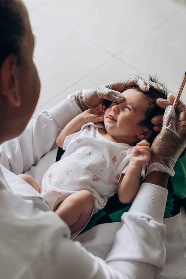 A healthcare professional examines a newborn baby indoors, demonstrating care and attention.