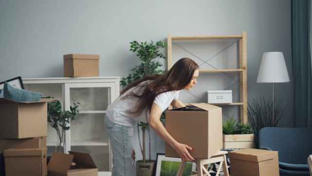 A young woman with long hair arranging boxes in her new home. Ideal for moving and lifestyle stories.